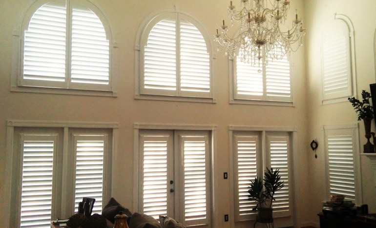 TV room in two-story Boise home with plantation shutters on tall windows.