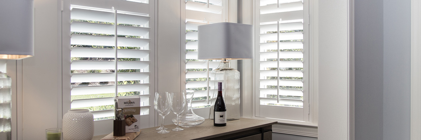 White polywood shutters in a corner of a dining room.