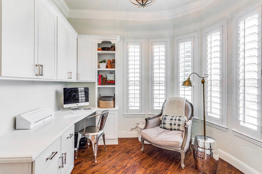 Bay windows with white Polywood shutters in an office/library setting.